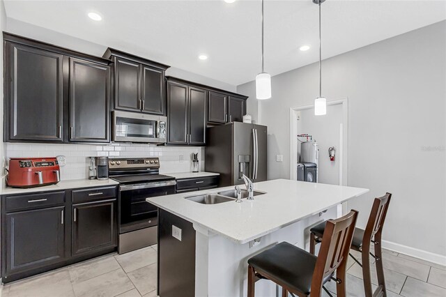 15096 Chapter Way, Winter Garden, FL 34787 - kitchen with appliances with stainless steel finishes, a sink, decorative backsplash, an island with sink, and light countertops
