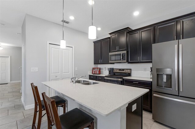 15096 Chapter Way, Winter Garden, FL 34787 - kitchen featuring stainless steel appliances, a sink, an island with sink, hanging light fixtures, and a breakfast bar area