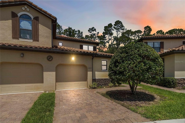 8219 Roseville Blvd, Davenport, FL 33896 - mediterranean / spanish house featuring a tile roof, decorative driveway, stucco siding, and a garage