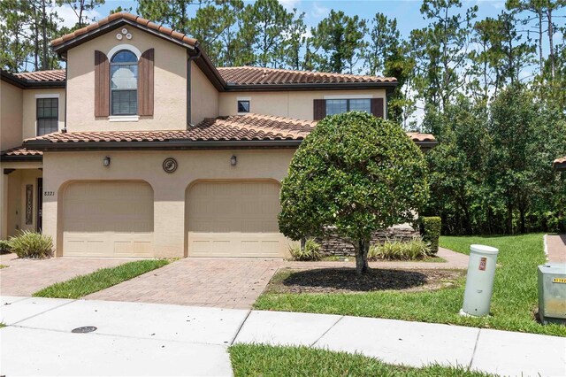 8219 Roseville Blvd, Davenport, FL 33896 - mediterranean / spanish-style home featuring a tile roof, decorative driveway, stucco siding, and a garage