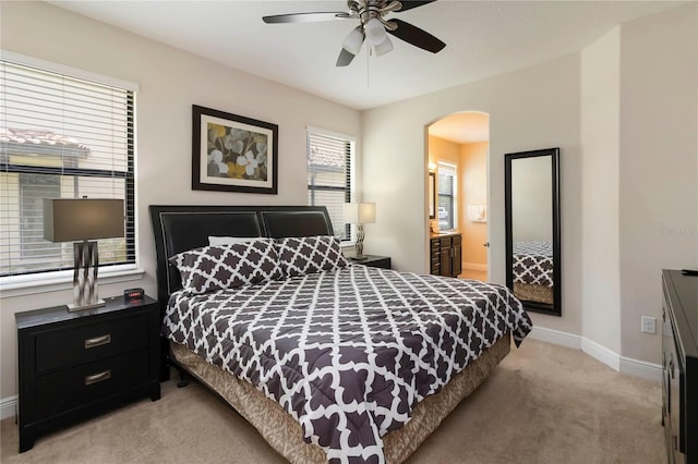 8219 Roseville Blvd, Davenport, FL 33896 - bedroom with light colored carpet, arched walkways, baseboards, a ceiling fan, and ensuite bath