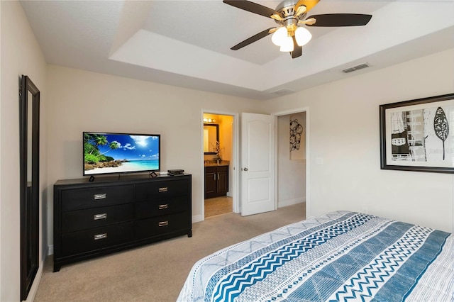 8219 Roseville Blvd, Davenport, FL 33896 - bedroom featuring light carpet, a tray ceiling, baseboards, connected bathroom, and a ceiling fan
