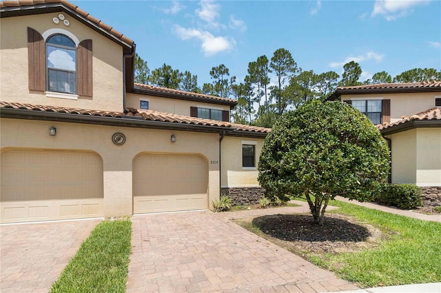 8219 Roseville Blvd, Davenport, FL 33896 - mediterranean / spanish-style home with a tiled roof, decorative driveway, an attached garage, and stucco siding
