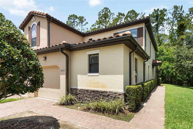 8219 Roseville Blvd, Davenport, FL 33896 - view of front of house featuring stucco siding, stone siding, decorative driveway, and a tiled roof