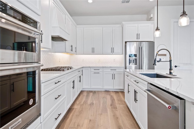 13323 Panama Beach Ct, Orlando, FL 32827 - kitchen featuring stainless steel appliances, a sink, white cabinetry, custom exhaust hood, and light wood finished floors
