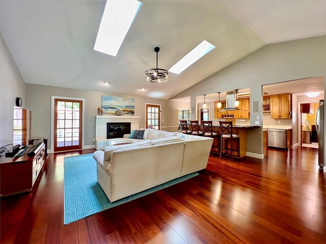 5724 Pitch Pine Dr, Orlando, FL 32819 - living room with a skylight, vaulted ceiling, a chandelier, dark wood-type flooring, and a glass covered fireplace