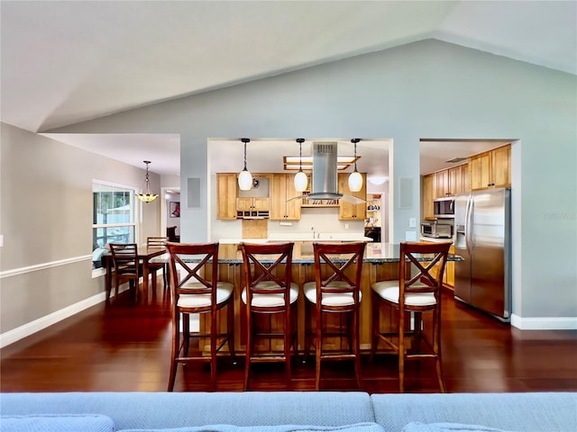5724 Pitch Pine Dr, Orlando, FL 32819 - kitchen with stainless steel appliances, island exhaust hood, vaulted ceiling, a kitchen bar, and dark wood finished floors