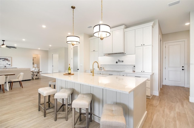 508 Topsail Dr, Rockledge, FL 32955 - kitchen with white cabinets, black electric cooktop, a breakfast bar area, light wood finished floors, and recessed lighting
