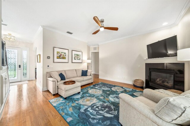 1420 Palmer Ave, Winter Park, FL 32789 - living room featuring light wood-style floors, a ceiling fan, crown molding, baseboards, and a glass covered fireplace