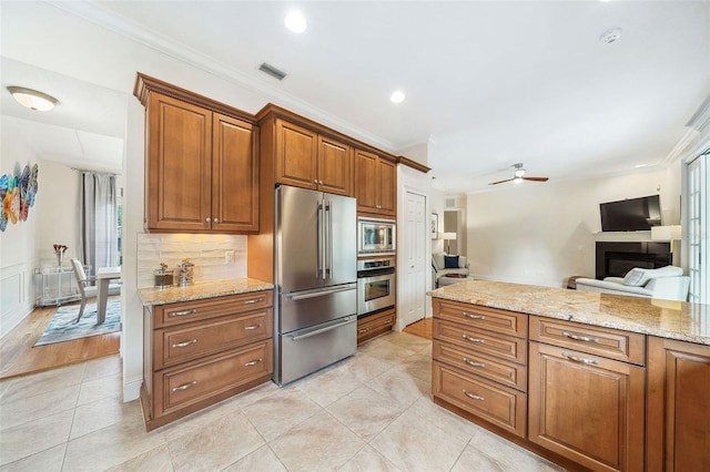 1420 Palmer Ave, Winter Park, FL 32789 - kitchen featuring appliances with stainless steel finishes, brown cabinetry, crown molding, light tile patterned floors, and a fireplace
