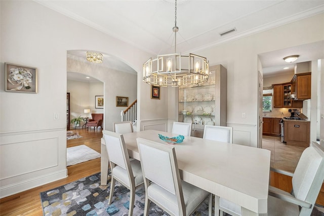 1420 Palmer Ave, Winter Park, FL 32789 - dining room featuring arched walkways, a chandelier, light wood finished floors, wainscoting, and crown molding