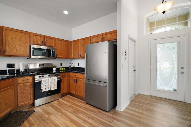 2306 Valhalla Dr, Tavares, FL 32778 - kitchen featuring appliances with stainless steel finishes, brown cabinetry, light wood-style floors, recessed lighting, and a high ceiling