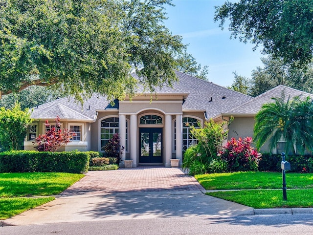 3216 Rolling Hills Ln, Apopka, FL 32712 - view of front facade with french doors, stucco siding, a front lawn, and roof with shingles
