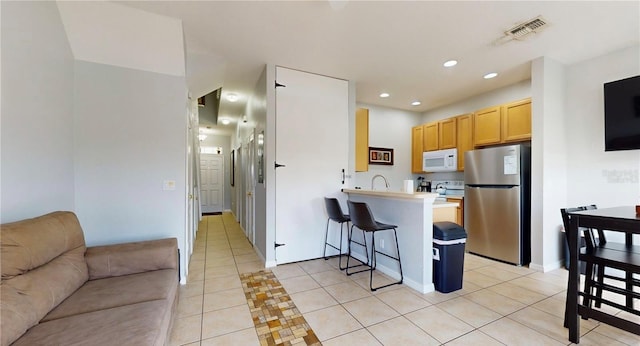 2411 Caravelle Cir, Kissimmee, FL 34746 - kitchen featuring white appliances, light tile patterned floors, a peninsula, open floor plan, and a breakfast bar area