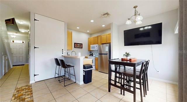 2411 Caravelle Cir, Kissimmee, FL 34746 - kitchen featuring white appliances, a peninsula, a breakfast bar, recessed lighting, and light tile patterned flooring