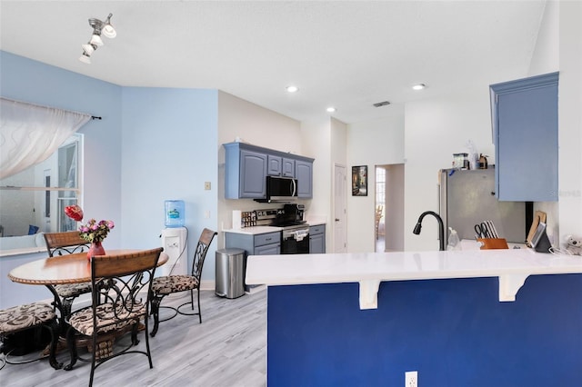 10743 Fairhaven Way, Orlando, FL 32825 - kitchen with appliances with stainless steel finishes, a peninsula, a breakfast bar area, light wood-style flooring, and recessed lighting