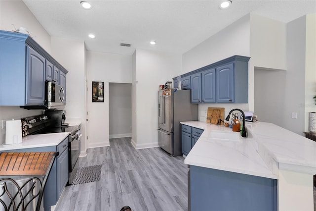 10743 Fairhaven Way, Orlando, FL 32825 - kitchen with appliances with stainless steel finishes, a sink, a peninsula, blue cabinets, and light wood-style flooring