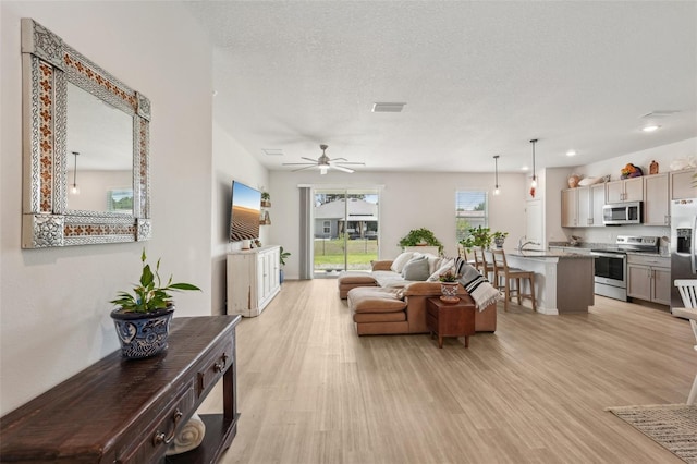 1909 Thomasville Ave SE, Palm Bay, FL 32909 - living area featuring light wood-style flooring, ceiling fan, and a textured ceiling