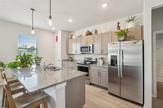 1909 Thomasville Ave SE, Palm Bay, FL 32909 - kitchen featuring stainless steel appliances, a sink, light wood-style floors, a breakfast bar area, and light stone countertops