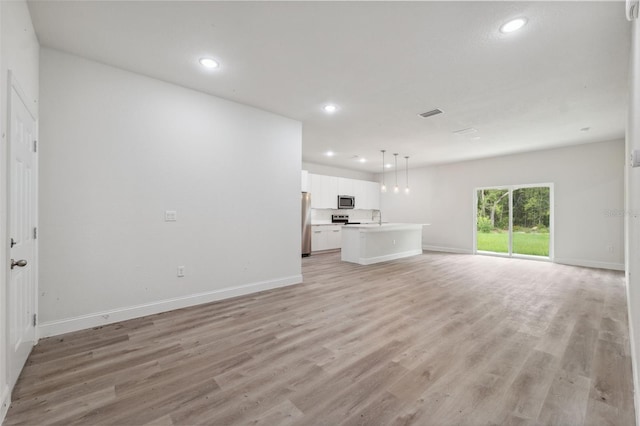 8944 N Pitcairn Way, Citrus Springs, FL 34434 - unfurnished living room featuring light wood finished floors, recessed lighting, baseboards, and a sink