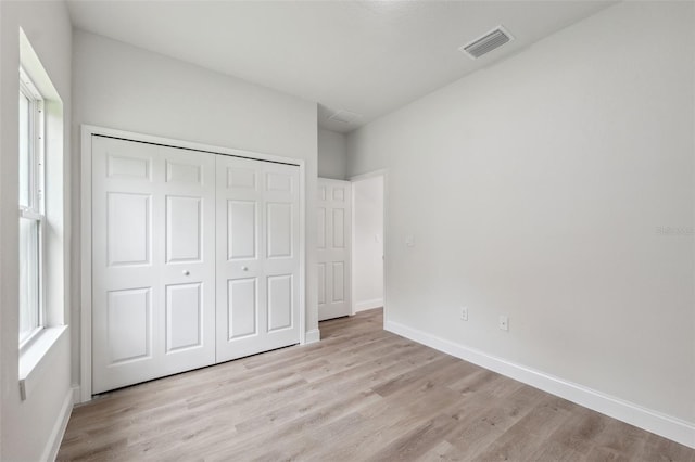 8944 N Pitcairn Way, Citrus Springs, FL 34434 - unfurnished bedroom with light wood finished floors, a closet, baseboards, and multiple windows