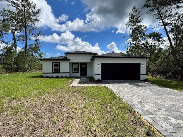 16463 SW 55th Court Rd, Ocala, FL 34473 - prairie-style house featuring stucco siding, a garage, decorative driveway, and a front lawn