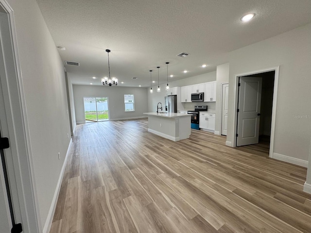 16463 SW 55th Court Rd, Ocala, FL 34473 - unfurnished living room featuring light wood-style floors, baseboards, a chandelier, recessed lighting, and a textured ceiling
