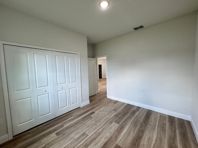16463 SW 55th Court Rd, Ocala, FL 34473 - unfurnished bedroom with wood finished floors, baseboards, a closet, and a textured ceiling