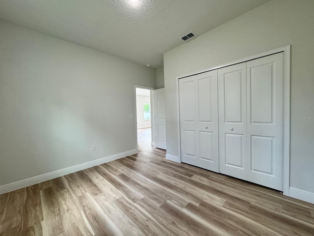 16463 SW 55th Court Rd, Ocala, FL 34473 - unfurnished bedroom featuring light wood-style floors, baseboards, a closet, and a textured ceiling