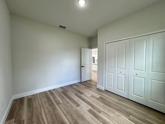 16463 SW 55th Court Rd, Ocala, FL 34473 - unfurnished bedroom with baseboards, light wood-style floors, a closet, and a textured ceiling