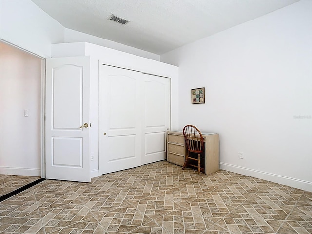 6843 Cherry Grove Cir, Orlando, FL 32809 - unfurnished bedroom featuring a closet, baseboards, and light stone finish flooring
