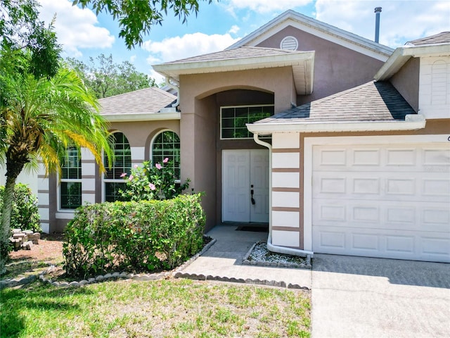 6843 Cherry Grove Cir, Orlando, FL 32809 - view of exterior entry with stucco siding, an attached garage, and a shingled roof
