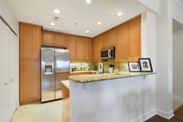 2305 Edgewater Dr Unit 1613, Orlando, FL 32804 - kitchen with appliances with stainless steel finishes, light stone counters, a peninsula, tasteful backsplash, and brown cabinets