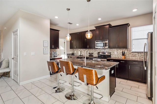 4740 Sleepy Hollow Dr, Kissimmee, FL 34746 - kitchen with stainless steel appliances, a sink, tasteful backsplash, a kitchen breakfast bar, and dark stone counters
