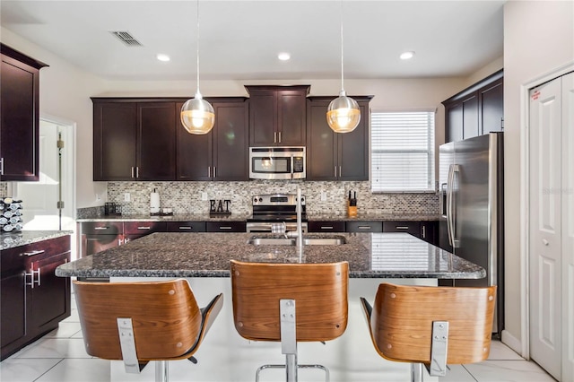 4740 Sleepy Hollow Dr, Kissimmee, FL 34746 - kitchen with stainless steel appliances, a sink, light tile patterned flooring, a kitchen island with sink, and decorative backsplash