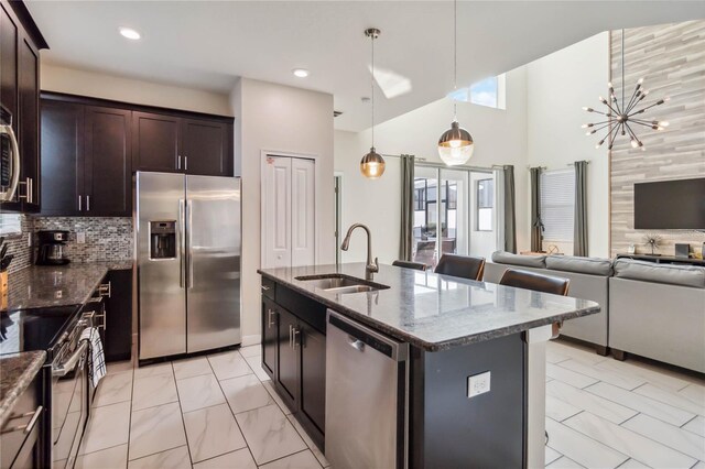 4740 Sleepy Hollow Dr, Kissimmee, FL 34746 - kitchen with stainless steel appliances, a sink, dark stone countertops, a towering ceiling, and recessed lighting