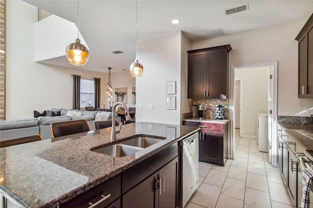 4740 Sleepy Hollow Dr, Kissimmee, FL 34746 - kitchen featuring a sink, stainless steel dishwasher, open floor plan, light marble finish floors, and dark stone counters
