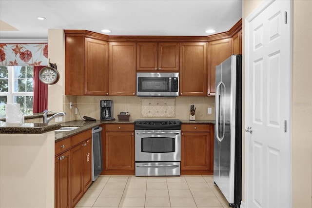 1100 Sunset View Cir Unit 204, Reunion, FL 34747 - kitchen featuring appliances with stainless steel finishes, a peninsula, light tile patterned floors, a sink, and dark stone counters