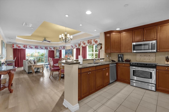 1100 Sunset View Cir Unit 204, Reunion, FL 34747 - kitchen with appliances with stainless steel finishes, a raised ceiling, a sink, a chandelier, and brown cabinetry