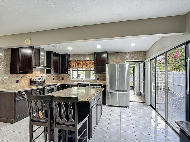 620 Wood Dr, Kissimmee, FL 34759 - kitchen featuring stainless steel appliances, wall chimney exhaust hood, light tile patterned floors, tasteful backsplash, and a sink