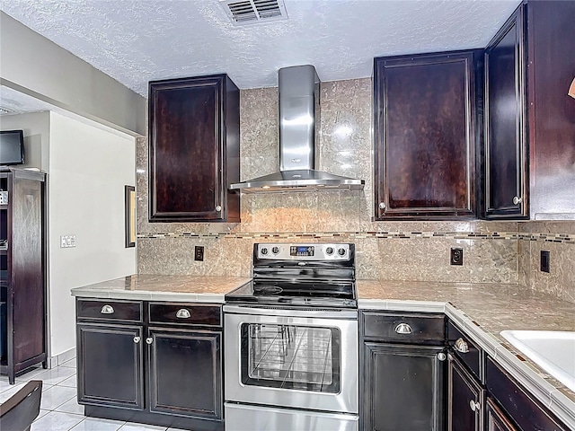 620 Wood Dr, Kissimmee, FL 34759 - kitchen featuring stainless steel range with electric stovetop, wall chimney range hood, light countertops, decorative backsplash, and a textured ceiling