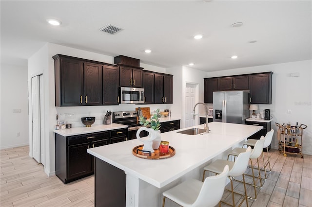 14357 Hidden Ct, Clermont, FL 34711 - kitchen with appliances with stainless steel finishes, a sink, light wood-style floors, a breakfast bar area, and recessed lighting