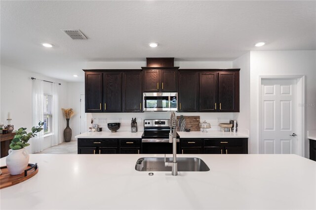 14357 Hidden Ct, Clermont, FL 34711 - kitchen featuring appliances with stainless steel finishes, a sink, light countertops, recessed lighting, and dark brown cabinetry