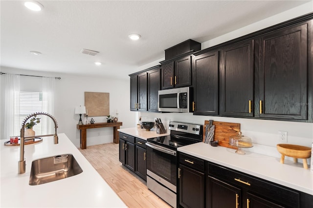 14357 Hidden Ct, Clermont, FL 34711 - kitchen featuring stainless steel appliances, a sink, light countertops, light wood-type flooring, and recessed lighting