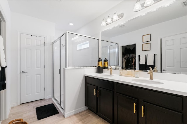 14357 Hidden Ct, Clermont, FL 34711 - bathroom with double vanity, a shower stall, wood finished floors, a spacious closet, and recessed lighting