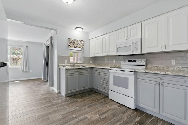 7214 Oakwood Dr, New Port Richey, FL 34652 - kitchen with white appliances, gray cabinetry, a sink, backsplash, and dark wood-style floors