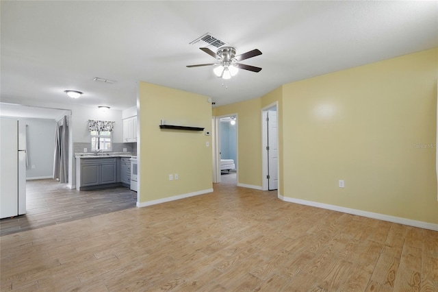 7214 Oakwood Dr, New Port Richey, FL 34652 - unfurnished living room featuring ceiling fan, light wood finished floors, a sink, and baseboards