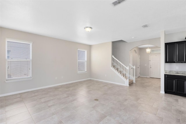 1978 J Lawson Blvd, Orlando, FL 32824 - unfurnished living room featuring arched walkways, stairway, plenty of natural light, and baseboards