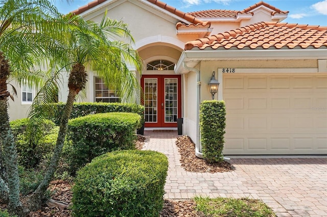 8418 Via Bella Notte, Orlando, FL 32836 - doorway to property with french doors, a garage, stucco siding, and decorative driveway