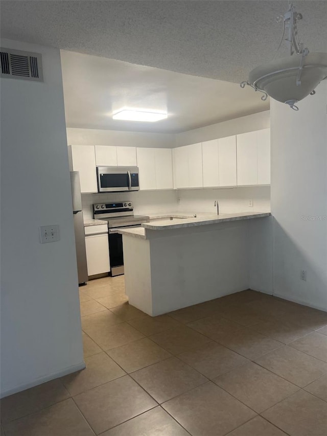 460 Sand Lime Rd, Winter Garden, FL 34787 - kitchen with appliances with stainless steel finishes, light tile patterned floors, white cabinetry, light countertops, and a peninsula